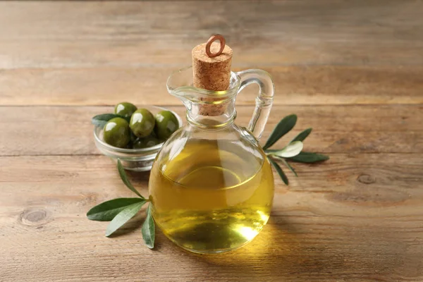 Glas Kanna Olja Mogna Oliver Och Gröna Blad Träbord Närbild — Stockfoto