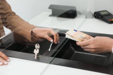 Adam bankadaki kasiyere para veriyor, yakın plan. Para birimi değişimi
