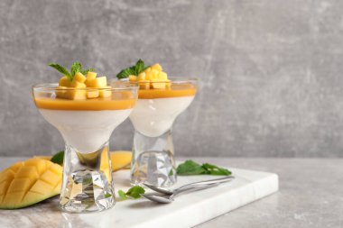 Açık gri masada servis edilen mango soslu nefis panna cotta. Metin için boşluk