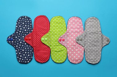 Açık mavi arka planda birçok yeniden kullanılabilir bez menstrüel pedleri düz yatıyordu.