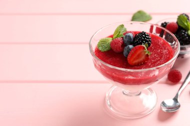 Meyve soslu lezzetli panna cotta ve pembe tahta masada servis edilen taze böğürtlenler. Metin için boşluk