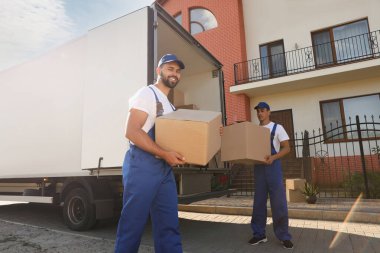 İşçiler açık hava minibüsünden kutuları boşaltıyor. Taşıma servisi