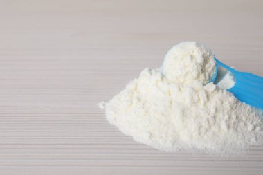 Toz bebek formülü ve beyaz ahşap masaya kepçe, yazı için yeri olan yakın plan. Bebek sütü