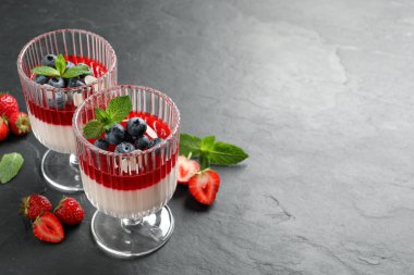 Meyve soslu lezzetli panna cotta ve koyu gri masada taze böğürtlen. Metin için boşluk