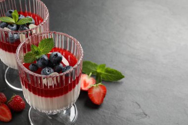 Meyve soslu lezzetli panna cotta ve koyu gri masada taze böğürtlen. Metin için boşluk