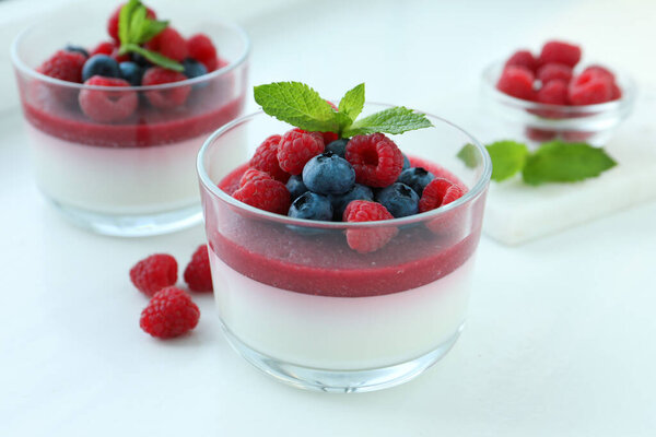 Delicious panna cotta with berries on white table