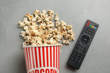 Modern TV uzaktan kumandası ve patlamış mısır gri masada, düz yerde.