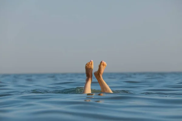 Drowning woman\'s legs sticking out of sea