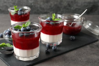 Meyve soslu lezzetli panna cotta ve gri masada servis edilen taze yaban mersini. Metin için boşluk