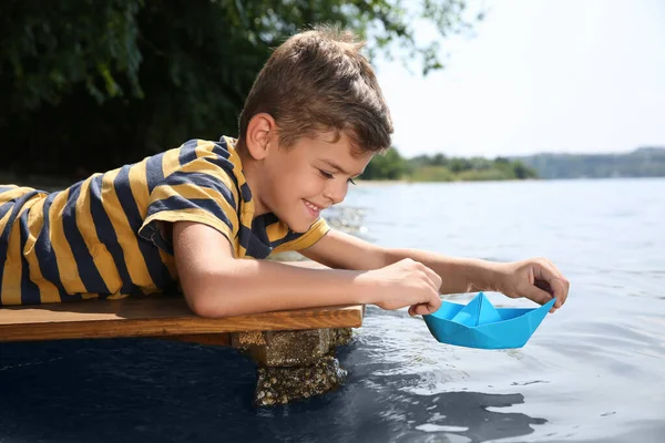 Menino Bonito Brincando Com Barco Papel Cais Madeira Perto Rio — Fotografia de Stock