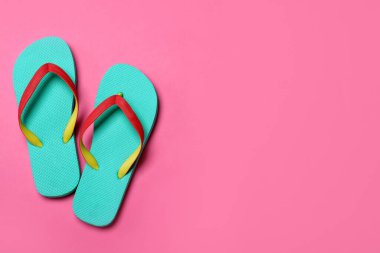 Pembe arka planda şık parmak arası terlikler, düz yatış. Metin için boşluk