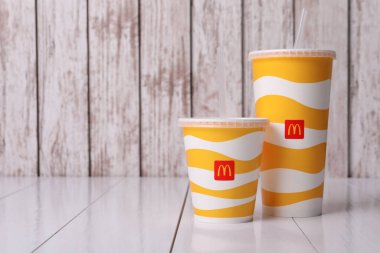 MYKOLAIV, UKRAINE - 12 Ağustos 2021: soğuk McDonald 's içecekleri beyaz ahşap masada. Metin için boşluk