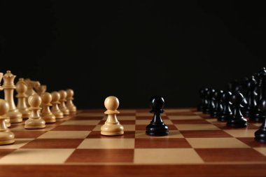 Siyah arka plana karşı tahta tahtadaki satranç taşları