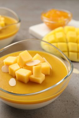 Mango soslu lezzetli panna cotta ve gri masada taze meyve parçaları, yakın plan.
