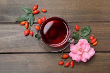 Düz kompozisyon ve ahşap masada aromatik gül kalçası çayı.