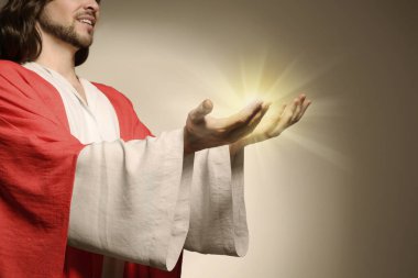 Jesus Christ on beige background, closeup. Miraculous light in hands clipart
