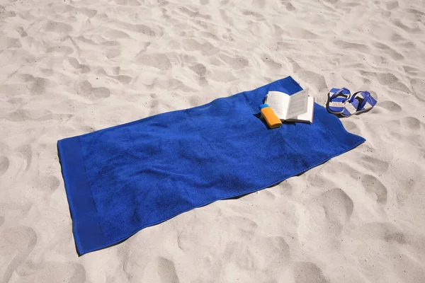 Zachte Blauwe Strandhanddoek Teenslippers Zonnebrandcrème Boek Zand — Stockfoto