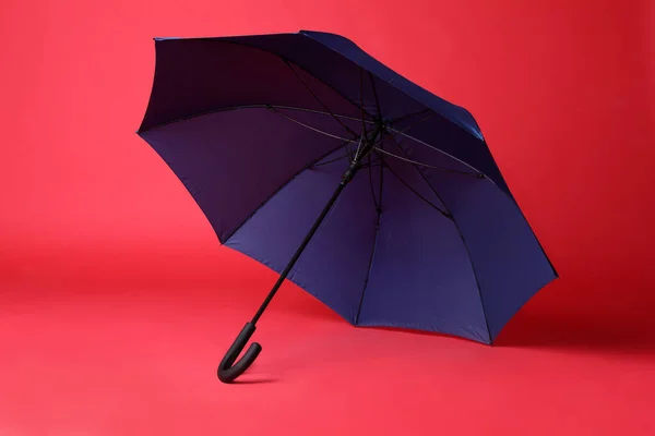 红色背景的时髦开朗的蓝色雨伞 — 图库照片