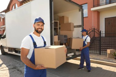 İşçiler açık hava minibüsünden kutuları boşaltıyor. Taşıma servisi