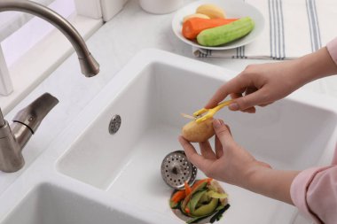Evdeki çöp öğütücüyle patates soyan kadın, yakın plan.