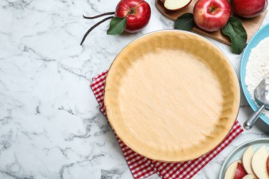 Hamur ve malzemelerle bembeyaz mermer masa üzerinde düz kompozisyon, yazı için boşluk. Elmalı turta yapıyorum.
