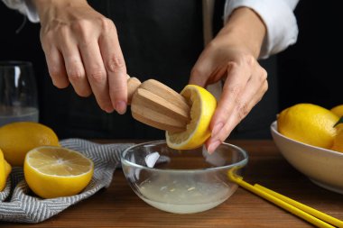 Ahşap masada limon suyu sıkan bir kadın, yakın plan.