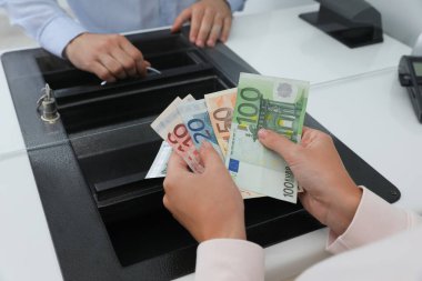 Bankadaki para biriminin vitrininde parası olan kadın, yakın plan.