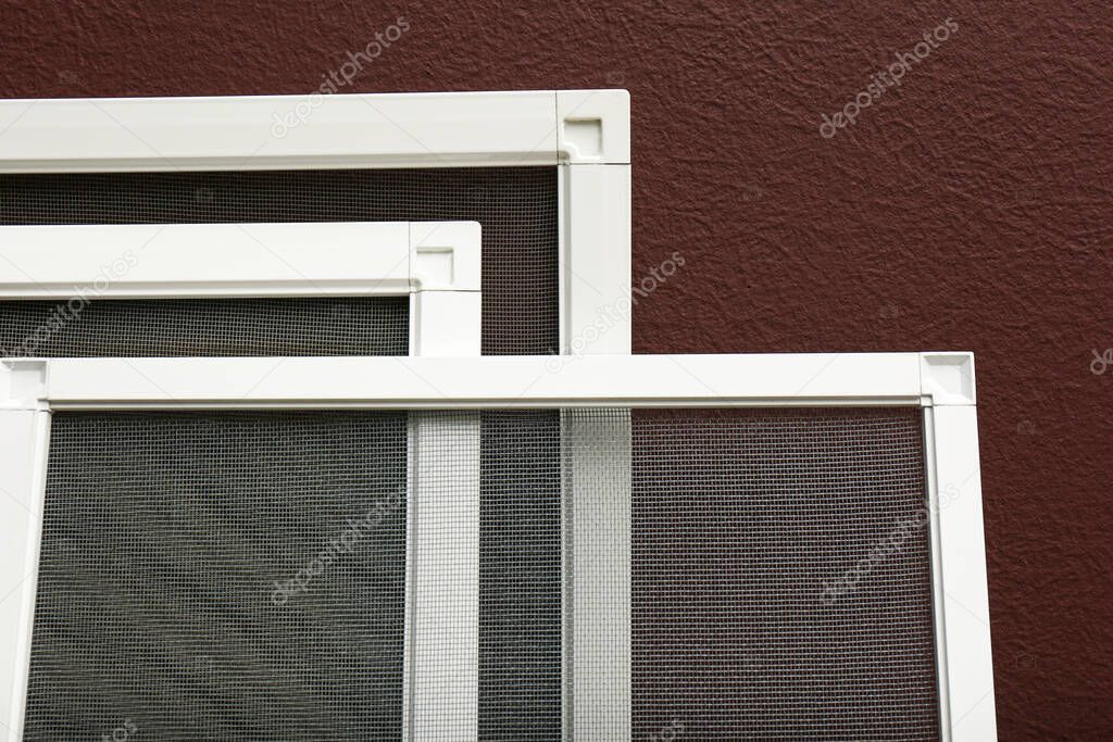 Set of window screens near brown wall, closeup