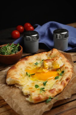 Tahta masadaki peynirli ve yumurtalı lezzetli Adjarian khachapuri.