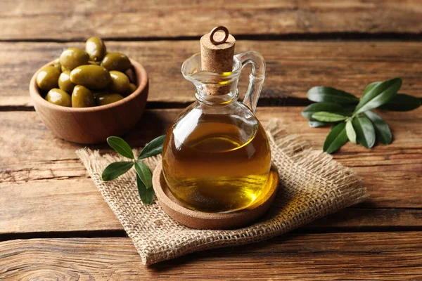 Glazen Kruik Met Olie Rijpe Olijven Groene Bladeren Houten Tafel — Stockfoto