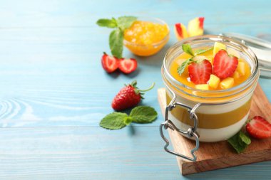 Mango soslu nefis panna cotta ve açık mavi ahşap masada taze meyveler. Metin için boşluk