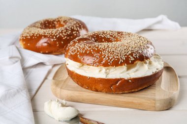 Beyaz ahşap masada krem peynirli leziz simit.