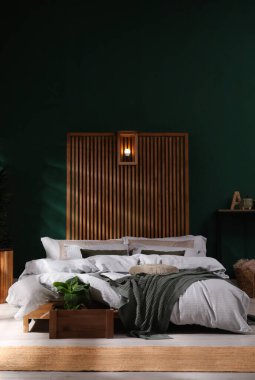 Geniş konforlu yatağı ve saksısı olan şık bir iç mekan.