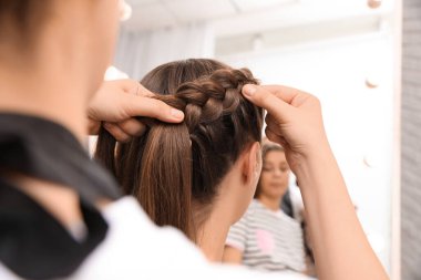 Profesyonel stilist, müşterinin saçını kuaförde örüyor, yakın plan.