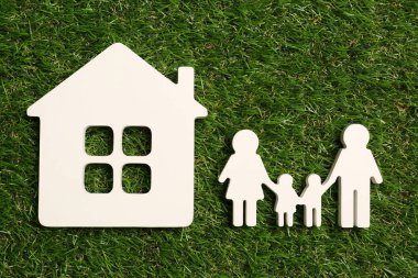 Yeşil çimenler üzerinde aile ve ev figürleri, düz uzanma