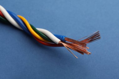 Mavi arka planda birçok bükülmüş elektrik kablosu, yakın plan
