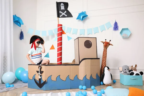 海賊の段ボールの船で双眼鏡で遊んでいる男の子 子供部屋のインテリア — ストック写真