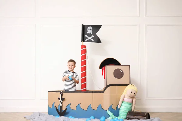 Netter Kleiner Junge Spielt Piratenpappschiff Nahe Weißer Wand Drinnen — Stockfoto