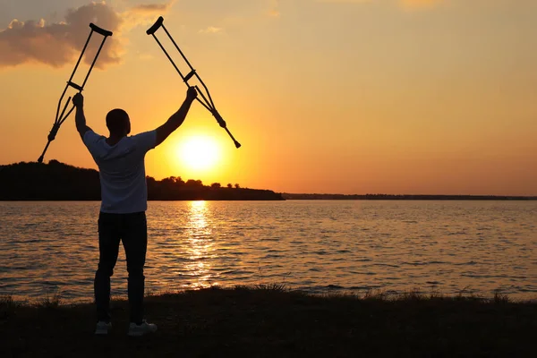 Man Steekt Handen Met Onderarmkrukken Tot Aan Hemel Bij Zonsondergang — Stockfoto