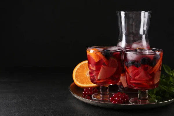 Delicious Red Sangria and ingredients on black table, space for text