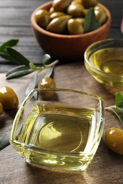 Cuencos Vidrio Aceite Aceitunas Maduras Hojas Verdes Sobre Mesa Madera —  Fotos de Stock