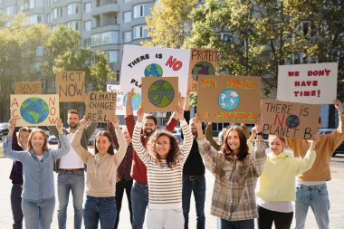 Şehir sokaklarında iklim değişikliğini protesto eden posterleri olan bir grup insan.