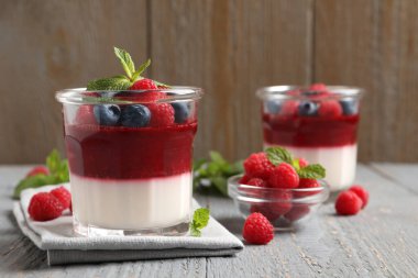 Gri ahşap masada böğürtlenli lezzetli panna cotta