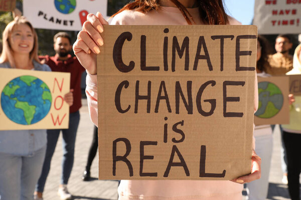 Woman with poster protesting against climate change outdoors, closeup