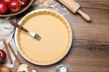 Hamur, çatal ve malzemelerle ahşap masa üzerinde düz kompozisyon, yazı için boşluk. Elmalı turta yapıyorum.