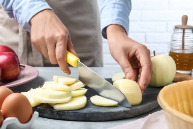 Gri masada elma kesen kadın, yakın plan. Pasta yapmak.