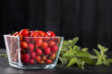 Siyah masada yeşil yapraklı olgun gül kalçası meyveleri. Metin için boşluk