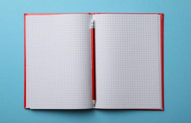 Açık mavi arkaplan üzerinde boş kağıtlar ve kalem olan bir defter aç, üst görünüm