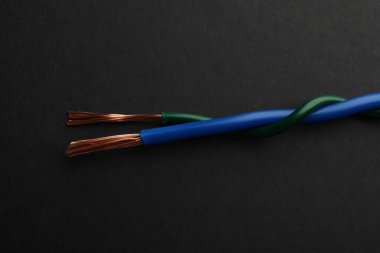 Siyah arka planda iki çarpık elektrik kablosu, yakın plan.