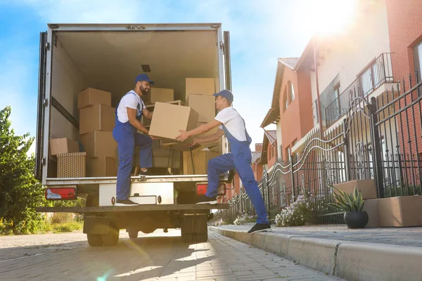 İşçiler açık hava minibüsünden kutuları boşaltıyor. Taşıma servisi